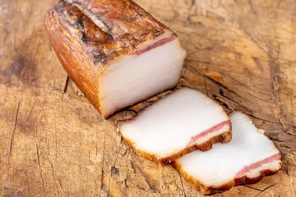 Sliced smoked lard on a wooden background (Flip 2020)