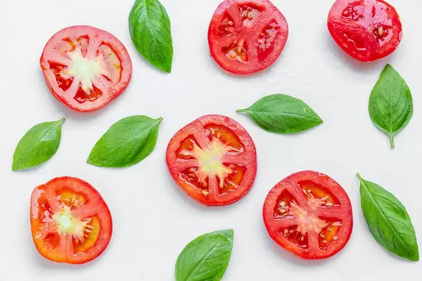 Sliced tomato and fresh Basil leaves on white background