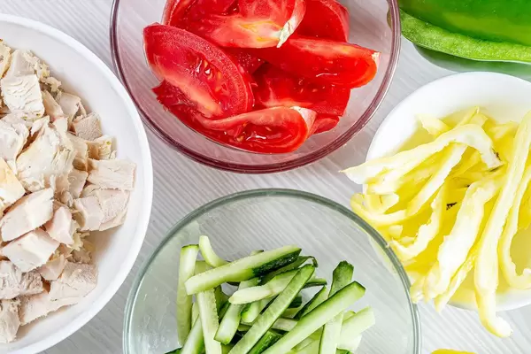 Sliced tomatoes, cucumbers, peppers and chicken fillet in glass bowls (Flip 2019)