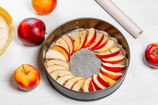 Slices of apples laid out on parchment paper in a baking sheet