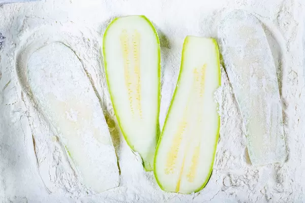 Slices of fresh zucchini in flour. Cooking concept