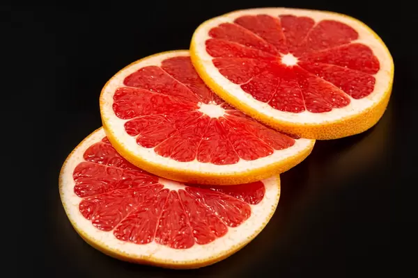 Slices of ripe fresh grapefruit on black background
