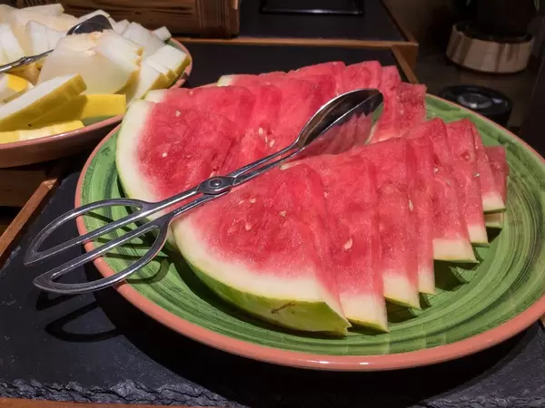 Slices of watermelon o a plate with tongs for serving