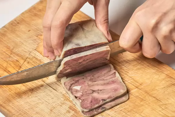 Slicing smoked meat product on cutting board