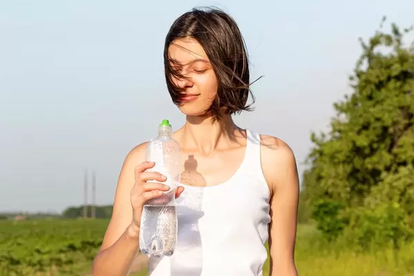 Slim brunette girl on nature with a bottle of water in hand