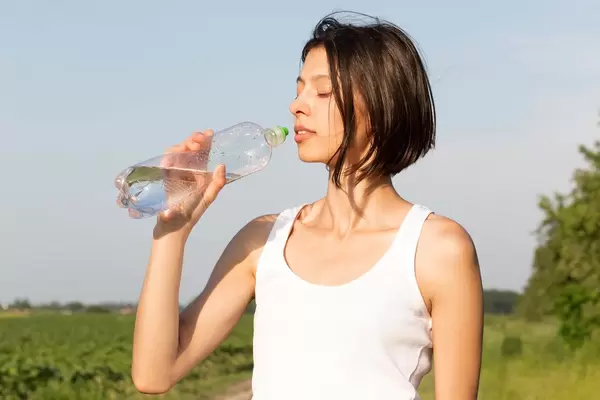 Slim young woman drinking water after training