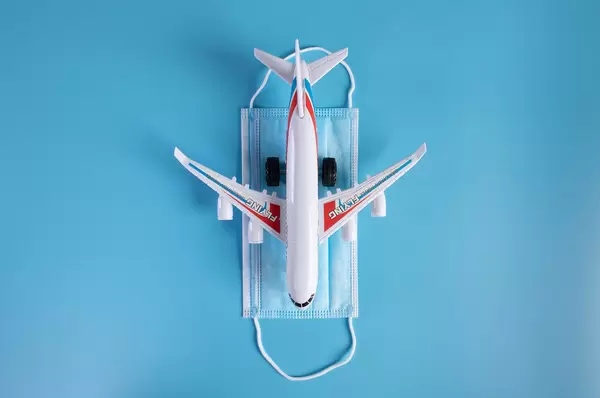 Small airplane on a medical face mask on blue background