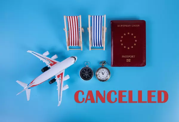 Small airplane, passport and beach chairs with Cancelled text on blue background