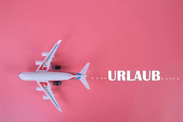 Small airplane with Urlaub text on pink background