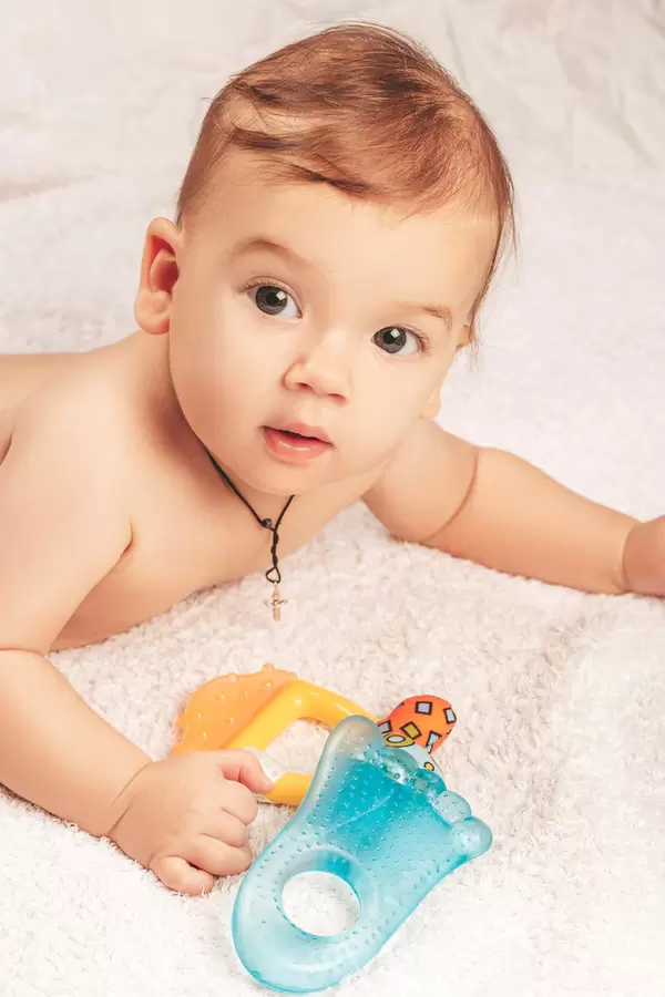 Small child with children's toys and a rattle on a soft blanket