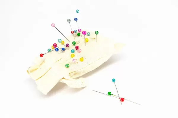 Small pillow with many colorful sewing pins inserted into it