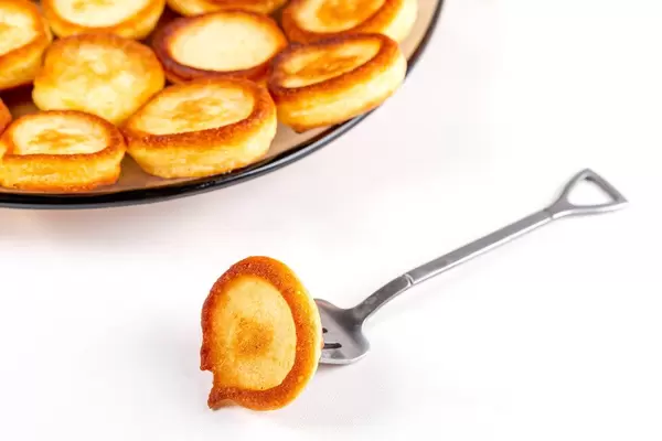 Small round pancake with fork on white background