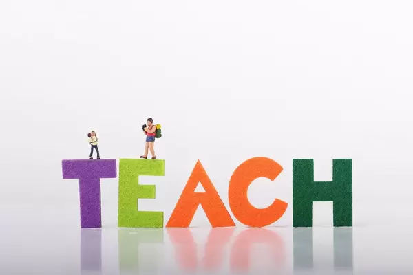 Small traveler figures with Teach text on white background