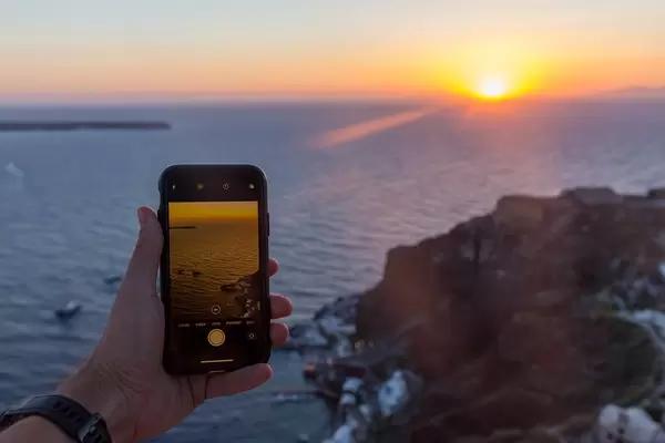 Smartphone-Fotografie in Urlaub: Mann mit iPhone in der Hand fotografiert den Sonnenuntergang