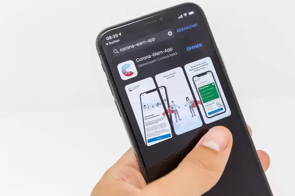 Smartphone mit der Corona-Warn-App in der Hand: die App hilft, Infektionsketten nachzuverfolgen