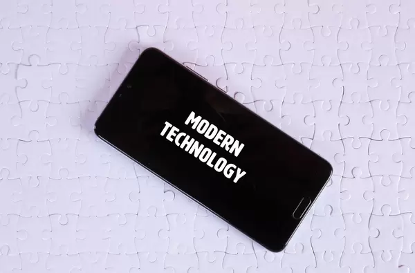 Smartphone on a white jigsaw puzzle with Modern Technology text