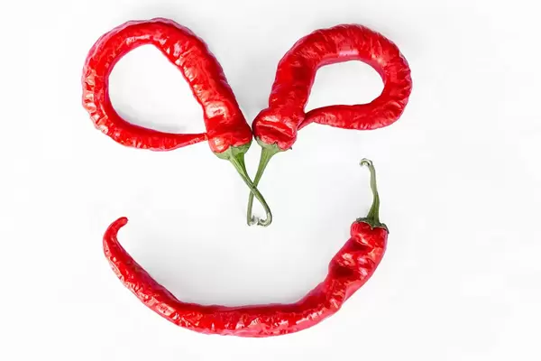 Smiling face made from chili peppers on white