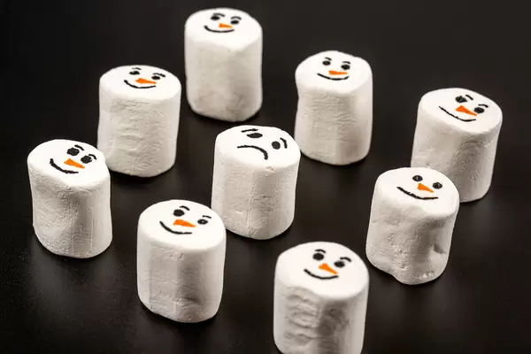 Smiling faces of marshmallow snowmen and one sad in the middle