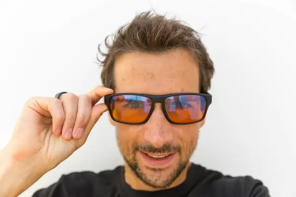 Smiling man wearing the computer glasses designed by Horus X for gamers and people who spend many hours in front of the screen