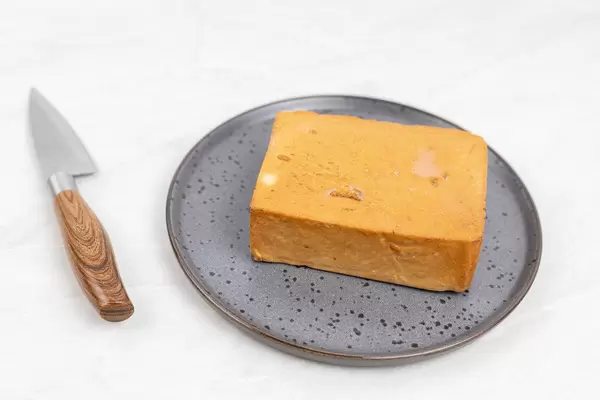 Smoked Cheese on the plate with knife on the table