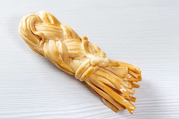 Smoked cheese Suluguni pigtail on white wooden background
