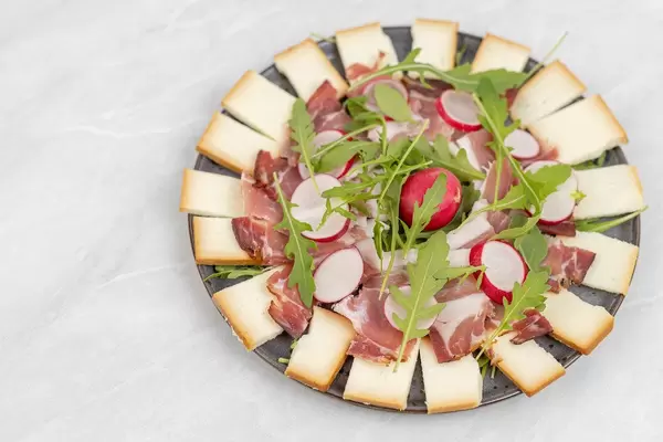 Smoked cheese with swiss ham and Rucola served on the plate