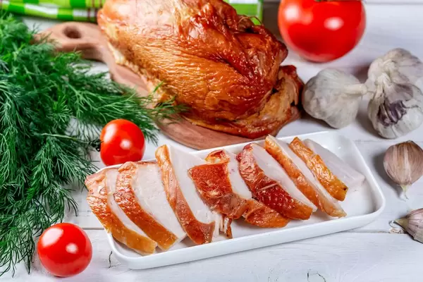 Smoked chicken with vegetables and herbs on a white wooden table
