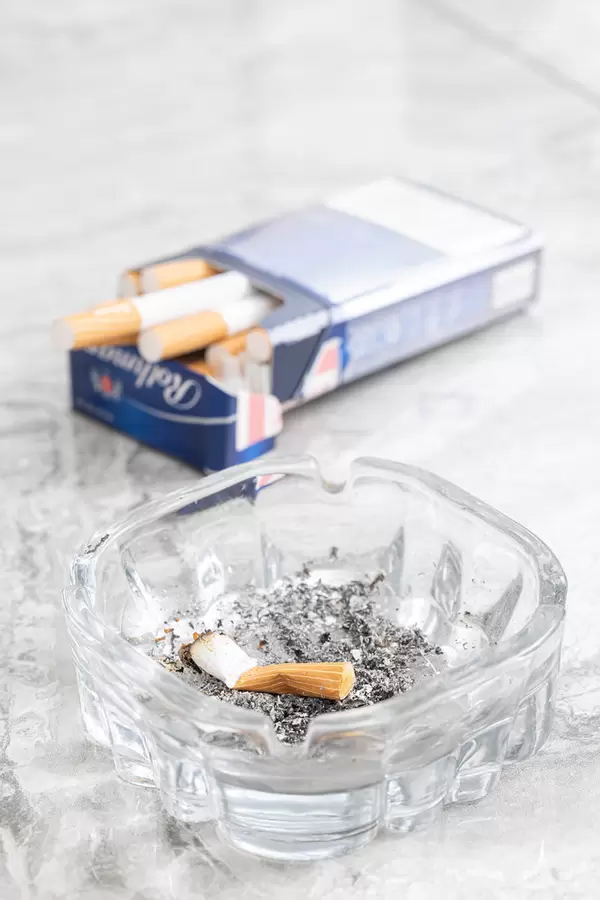Smoked Cigarette in the Ashtray with cigarettes in the blurred background