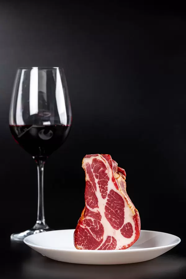 Smoked jerky with glass of red wine on black