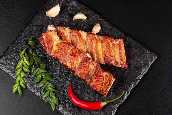 Smoked ribs with red pepper chili and garlic on black, top view