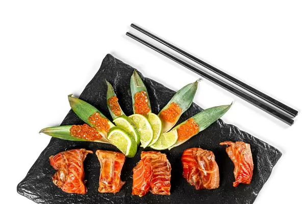 Smoked salmon fillet with lime and red caviar on green leaves