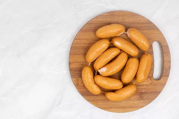 Smoked Sausages arranged on wooden board with copy space