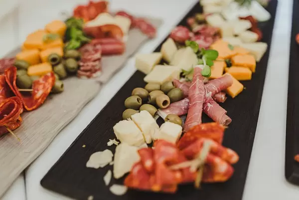 Snacks auf einem Hochzeit: Oliven, Schinken, Käse, Würstchen und getrocknete Tomaten auf schwarzem Brett