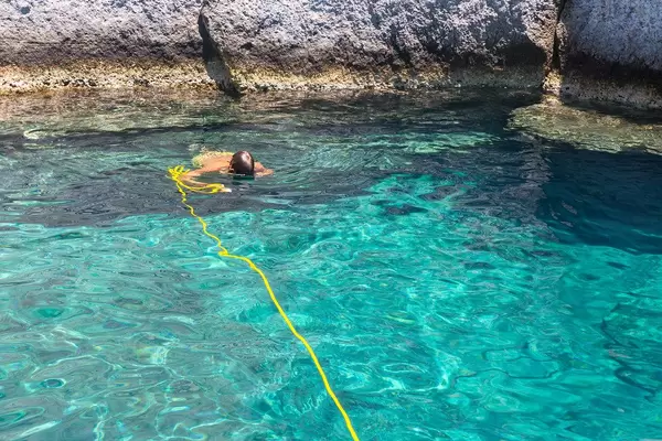 Snorkeling in turquoise waters during a stop of a boat excursion along the coast of Milos, Greece