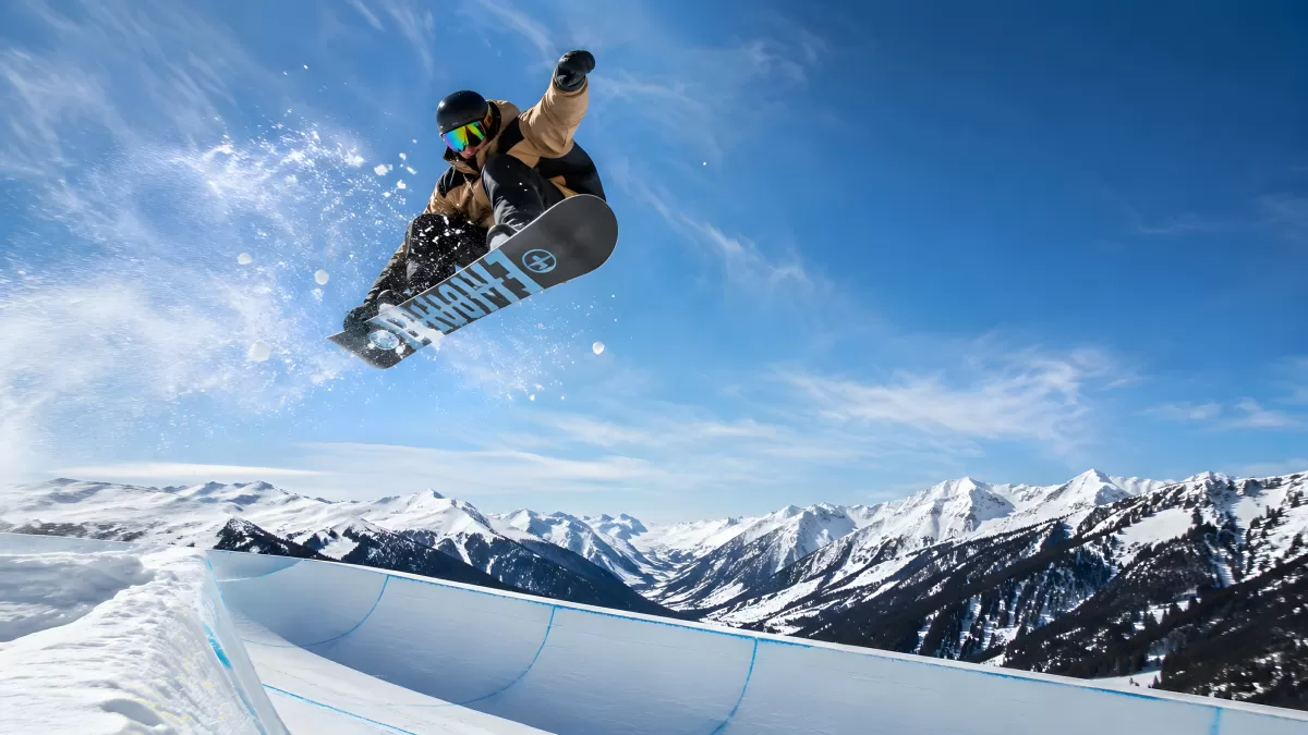 Snowboarder springt aus der Halfpipe vor Bergpanorama