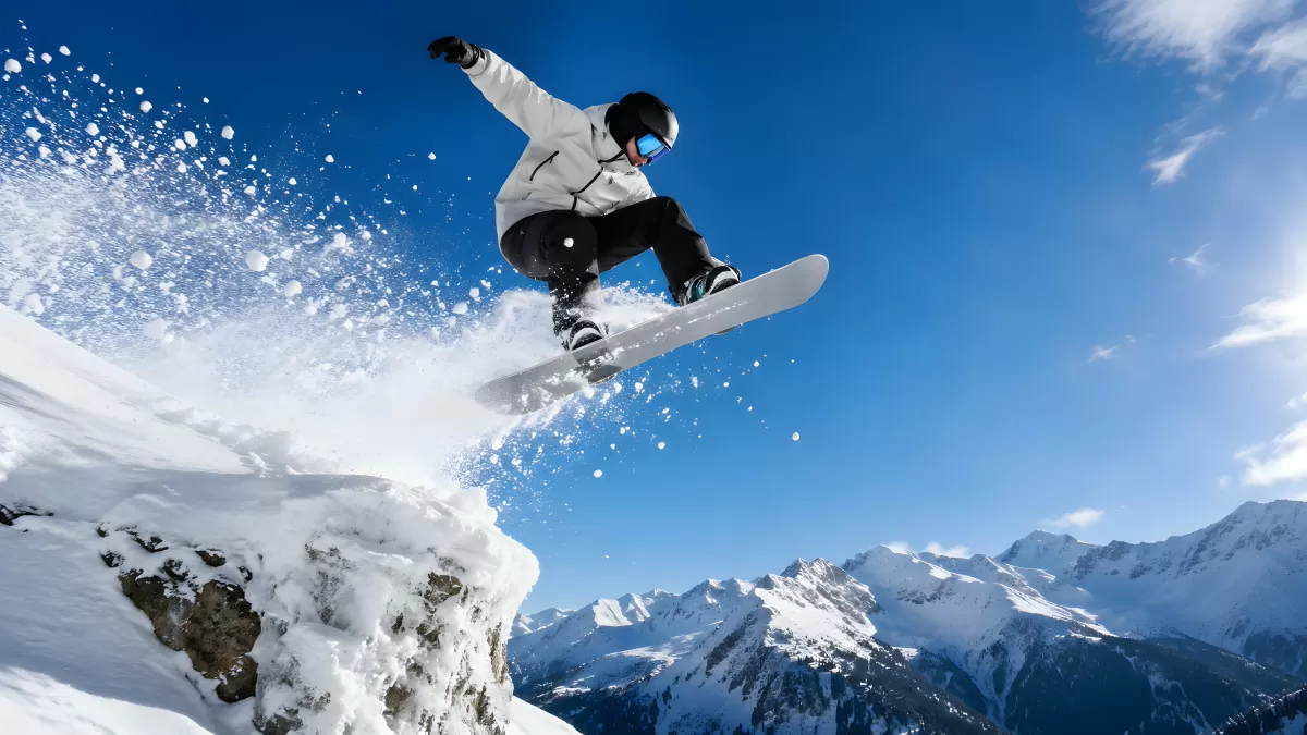 Snowboarder springt von Felsen in verschneiter Berglandschaft