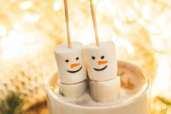 Snowmen made from marshmallows in a cup of hot coffee, close-up