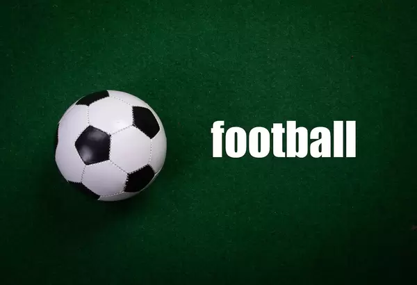 Soccer ball and football text on green grass