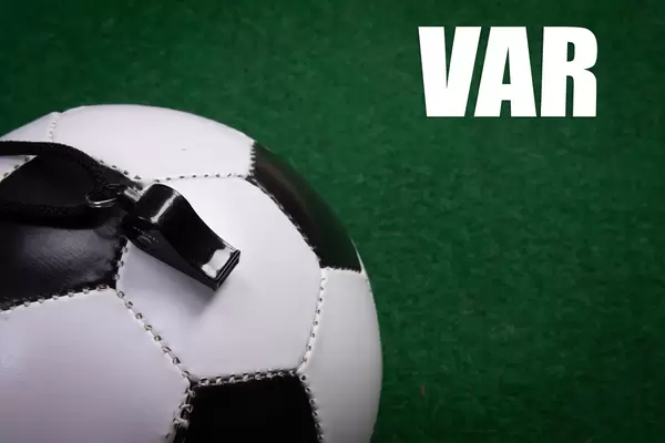 Soccer ball and VAR text on green grass