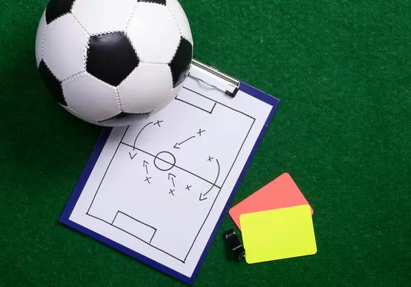 Soccer field tactics on a board with soccer ball and referee cards on green grass