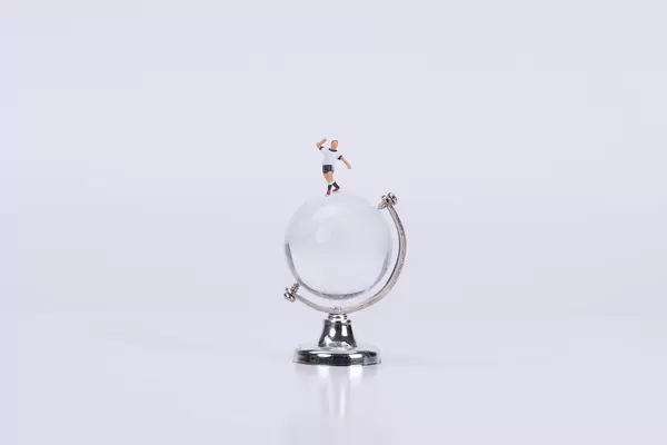 Soccer player standing on a glass globe