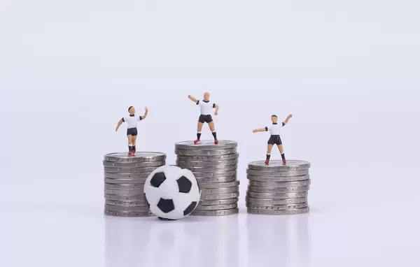 Soccer players standing on coinstacks
