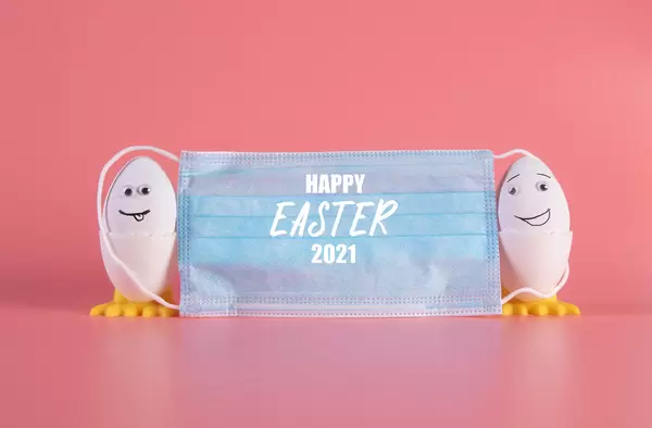 Social distancing concept with cute Easter eggs and medical face mask