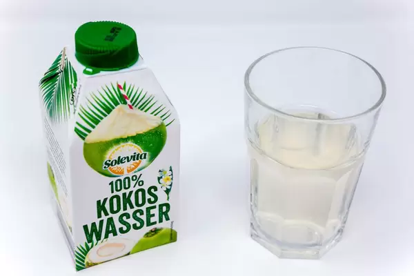 Solevita 100% Kokoswasser im Tetrapack neben einem gefüllten Glas