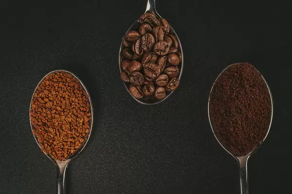 Soluble coffee, coffee beans and ground coffee isolated on black background, top view