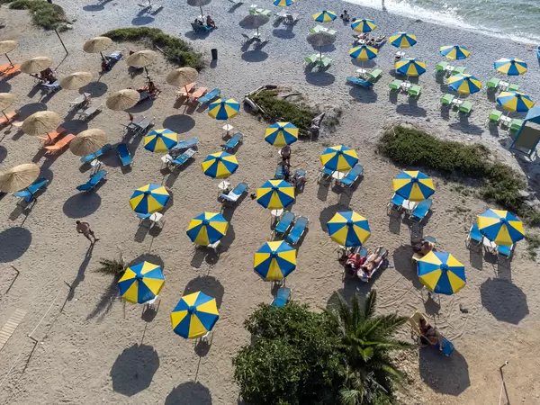Sommerurlaub 2021 in Griechenland mit Abstand zwischen den blau-gelben Sonnenschirmen am Strand Milia