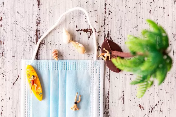 Sonne tanken und den Strand genießen. Urlauber im Sommer 2020. Aus dem Mundschutz wird ein Strand