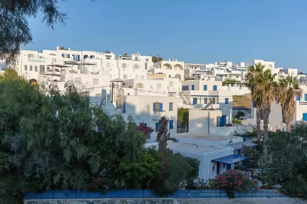 Sonnenschein über weißen Kalksteinhäusern und Wohnhäusern, neben Palmen, auf der Insel Paros in Griechenland