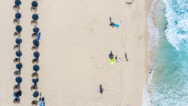 Sonnenschirme aus Stroh und Touristen. Overhead-Luftbild von Cala Mesquida Strand, Mallorca