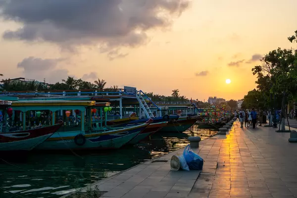 Sonnenuntergang am Flussufer des Thu Bon Fluss mit vielen angelegten Touristenbooten in der Altstadt von Hoi An, Vietnam